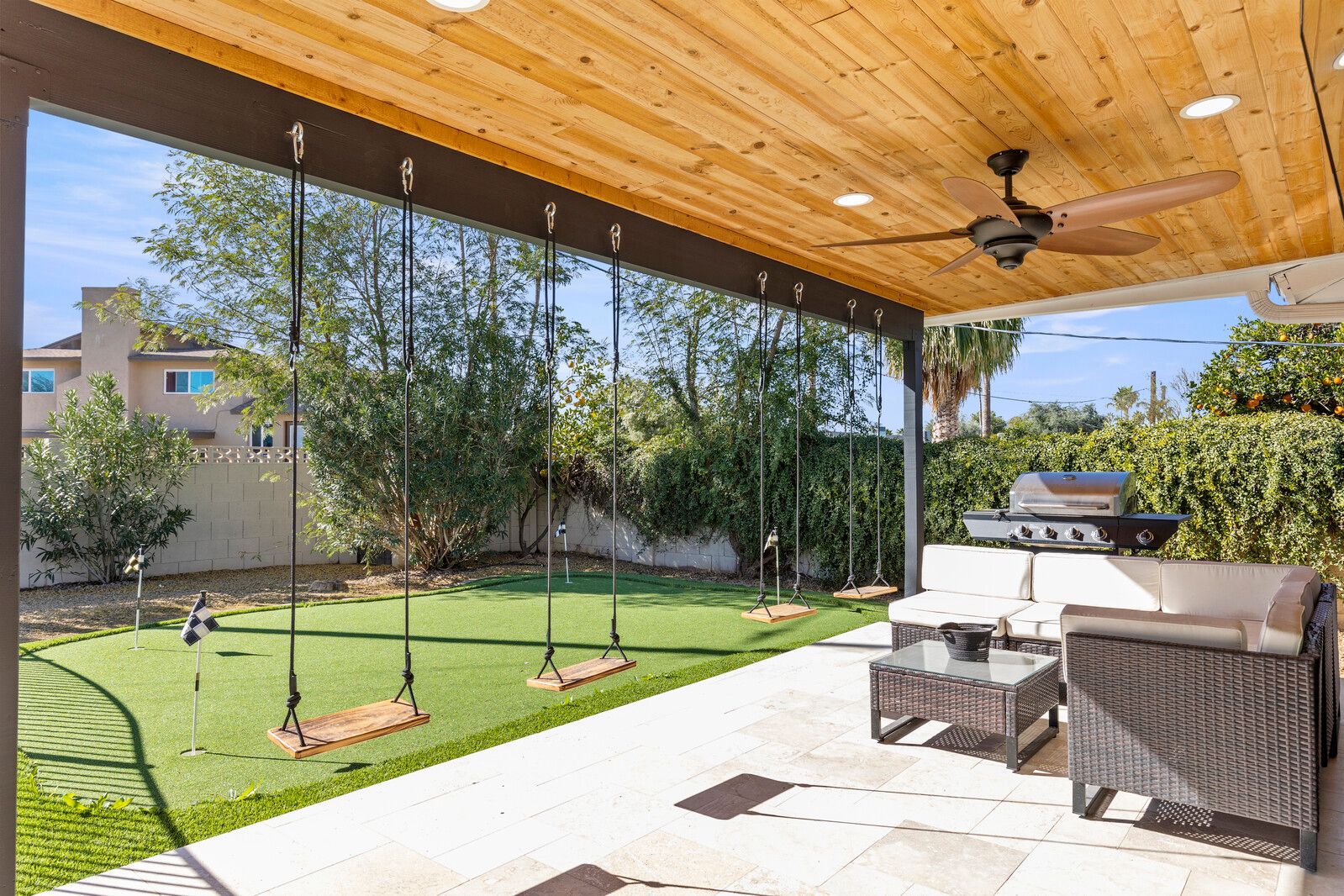 Azure Cove Vacation Rental Property by Rove Travel, located in Scottsdale Arizona. Backyard photo with grill, lounger set, swings, and putting green.